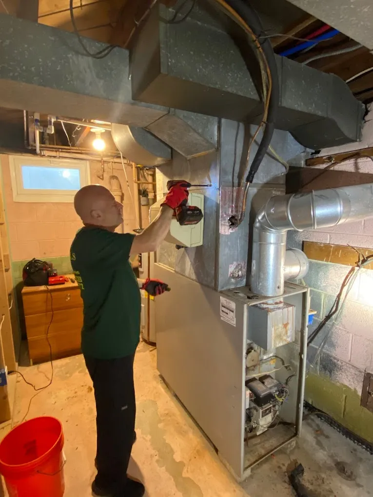 A man is focused on repairing a furnace in a workshop setting